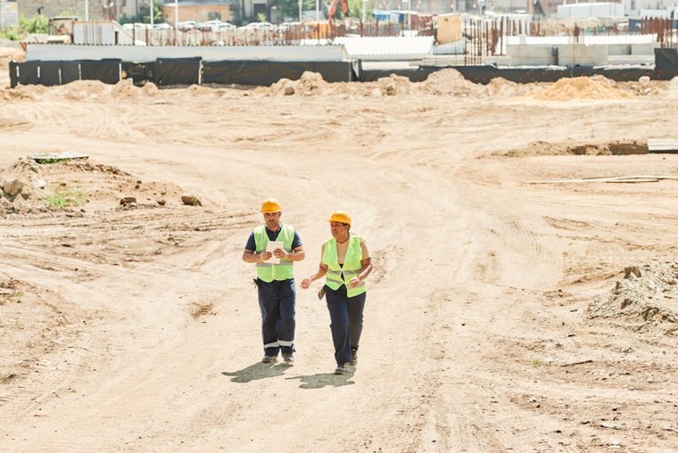 Two site engineers walking across a cleared construction site